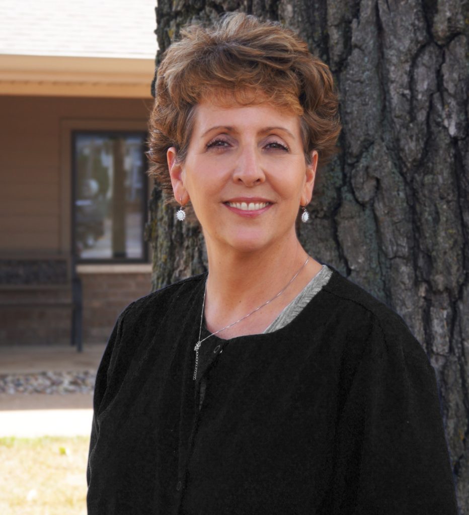 Stacy, dental assistant, smiling outdoors in front of a tree